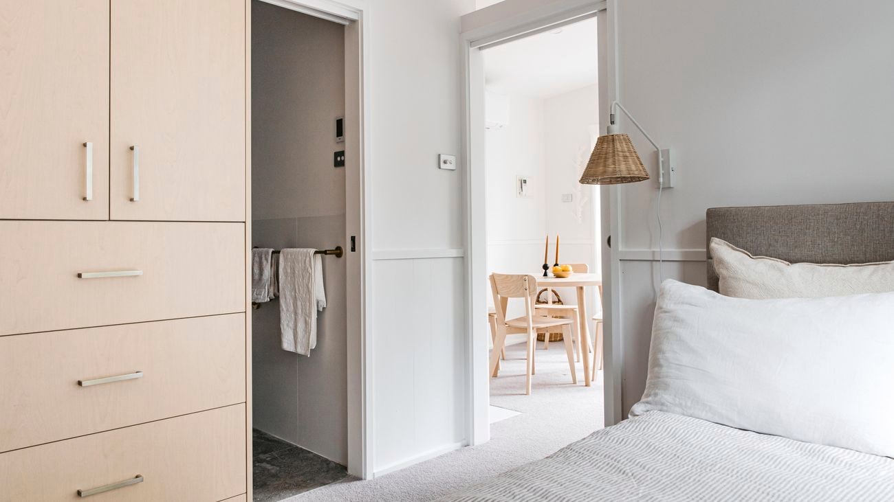 Bedroom in a granny flat, open doors show walkway to the living space and an ensuite