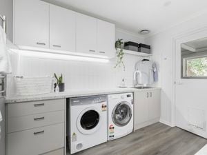 Laundry with cabinets, washer, dryer and timber flooring.