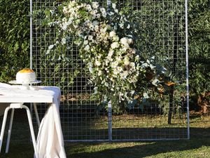 A floral wall made from wire panels adorned with white flowers.