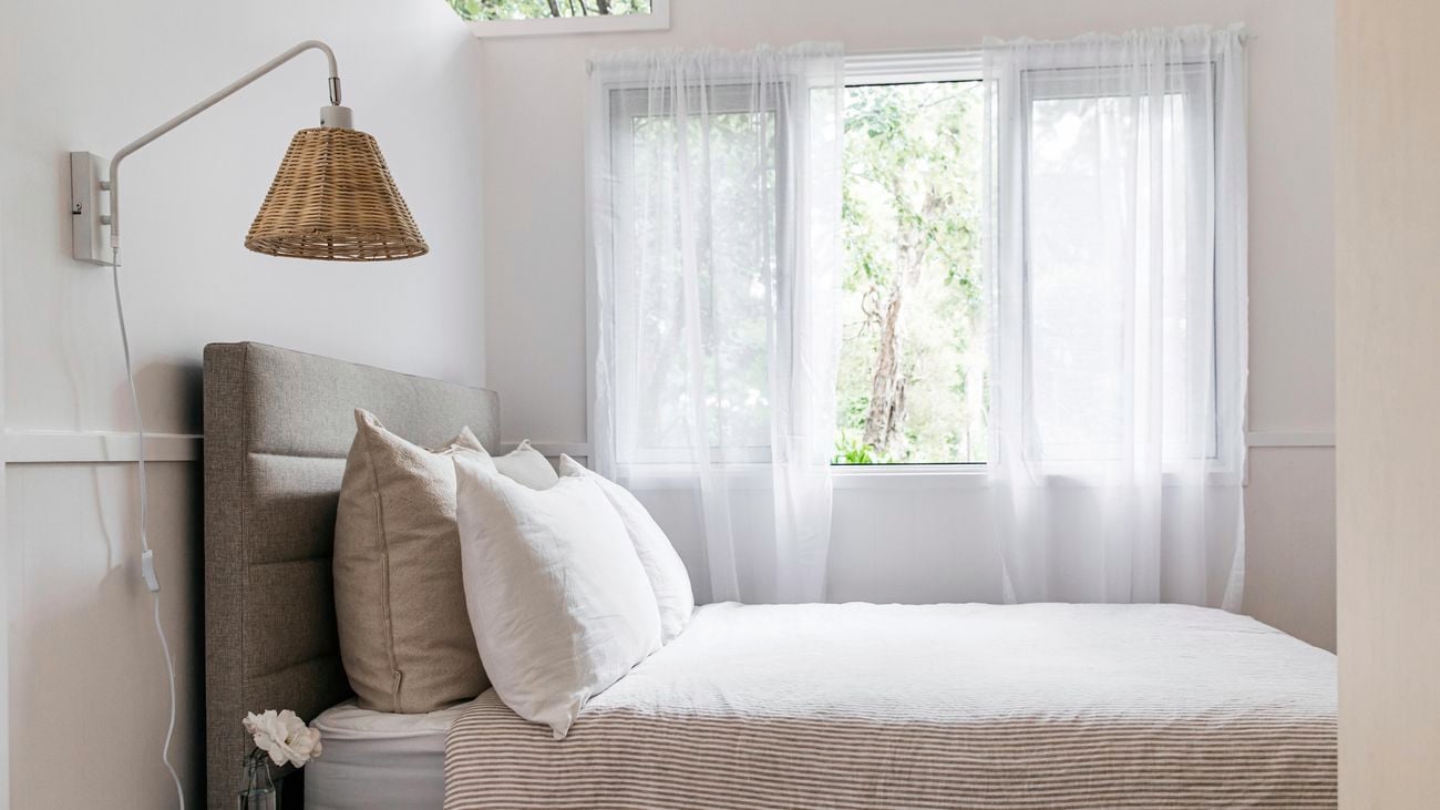 Light and airy modern bedroom featuring a rattan wall light