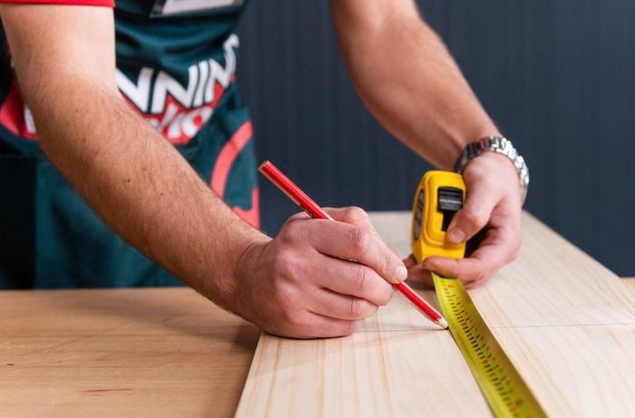 Bunnings team member measuring and marking timber with a pencil and measuring tape